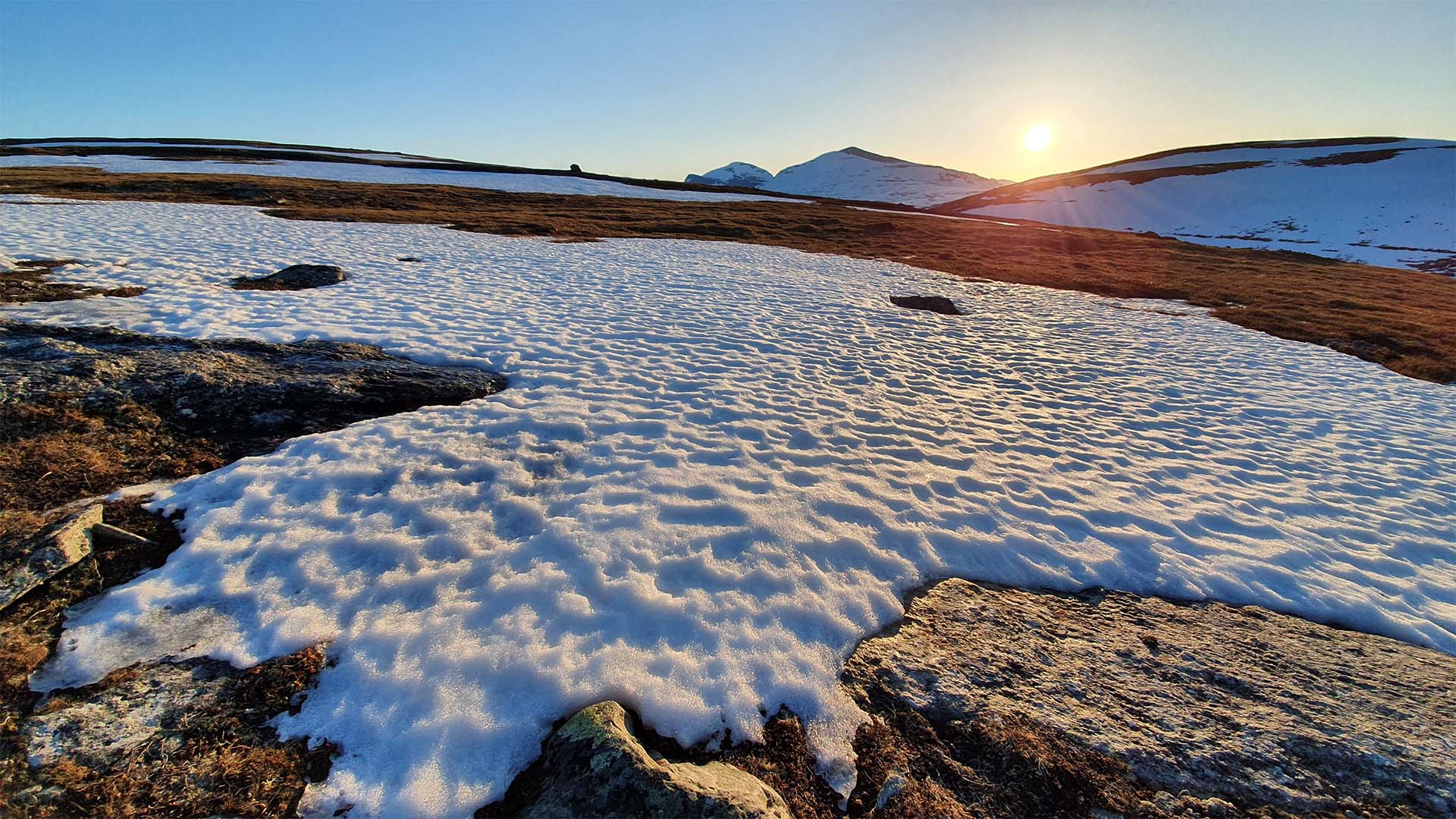 Snöskare på fjäll med solnedgång i bakgrunden